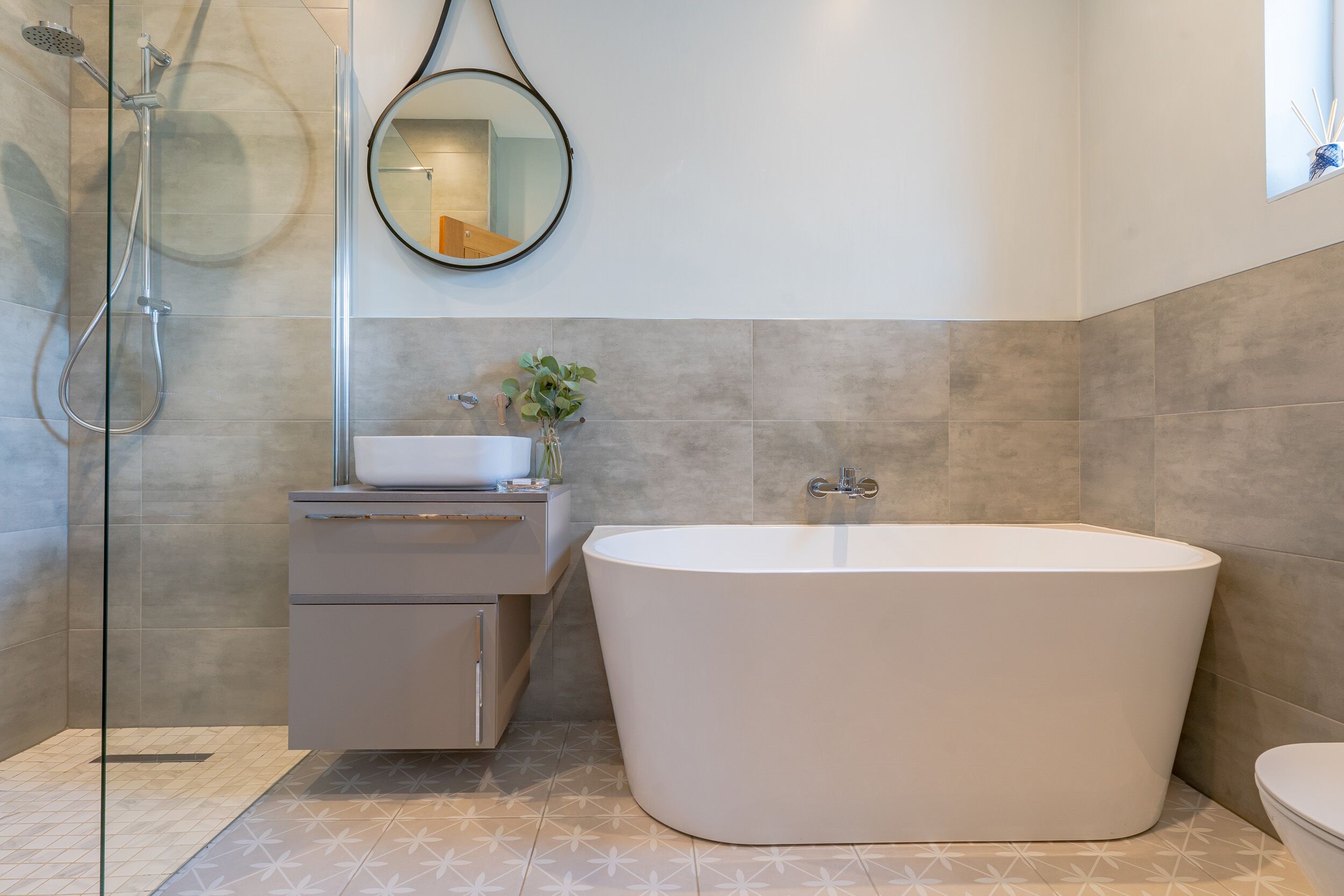 A modern bathroom with a freestanding bathtub, a glass-enclosed shower, and a vanity with a mirror.