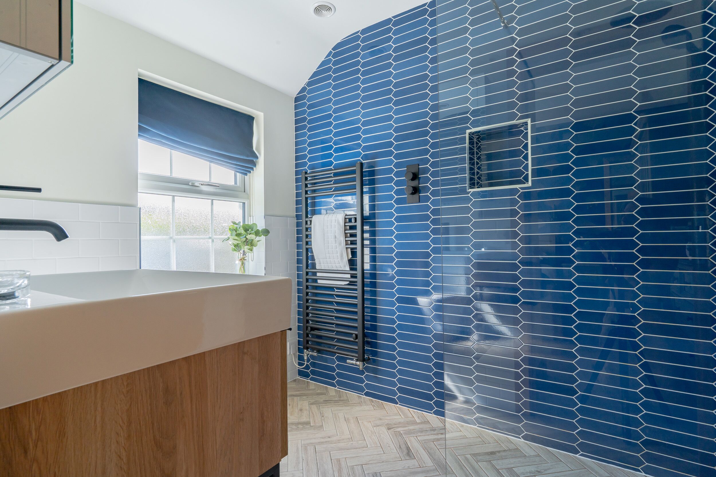 A modern kitchen with a white countertop, a wooden cabinet, and a blue-tiled backsplash.