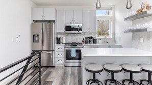 A modern kitchen with stainless steel appliances, a large island with bar stools, and a window providing natural light.