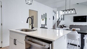 Une cuisine moderne équipée d’un lave-vaisselle, d’un évier et d’un coin repas avec une table et des chaises.