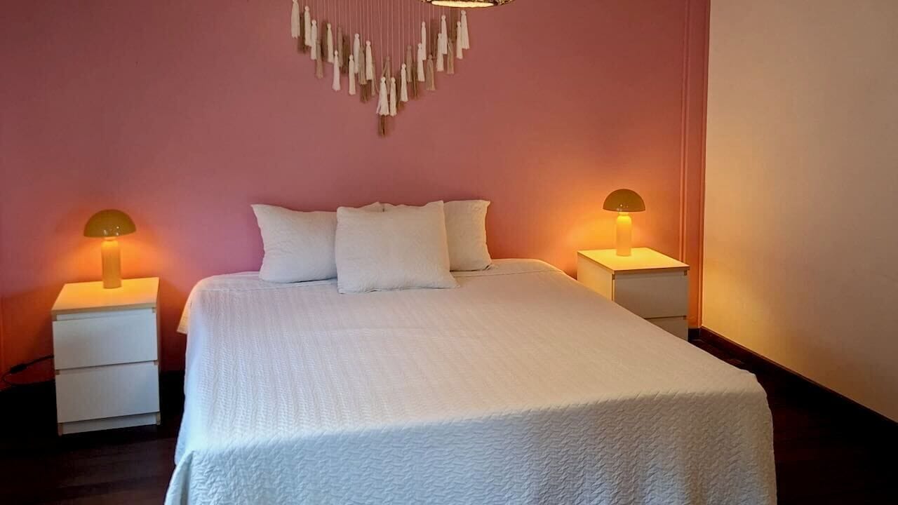 A bed with white bedding, two bedside tables, and wall-mounted lamps.