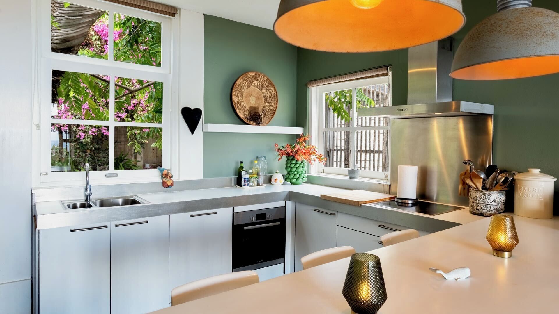 A modern kitchen with a built-in dishwasher, a stainless steel refrigerator, and a window with a view of greenery.