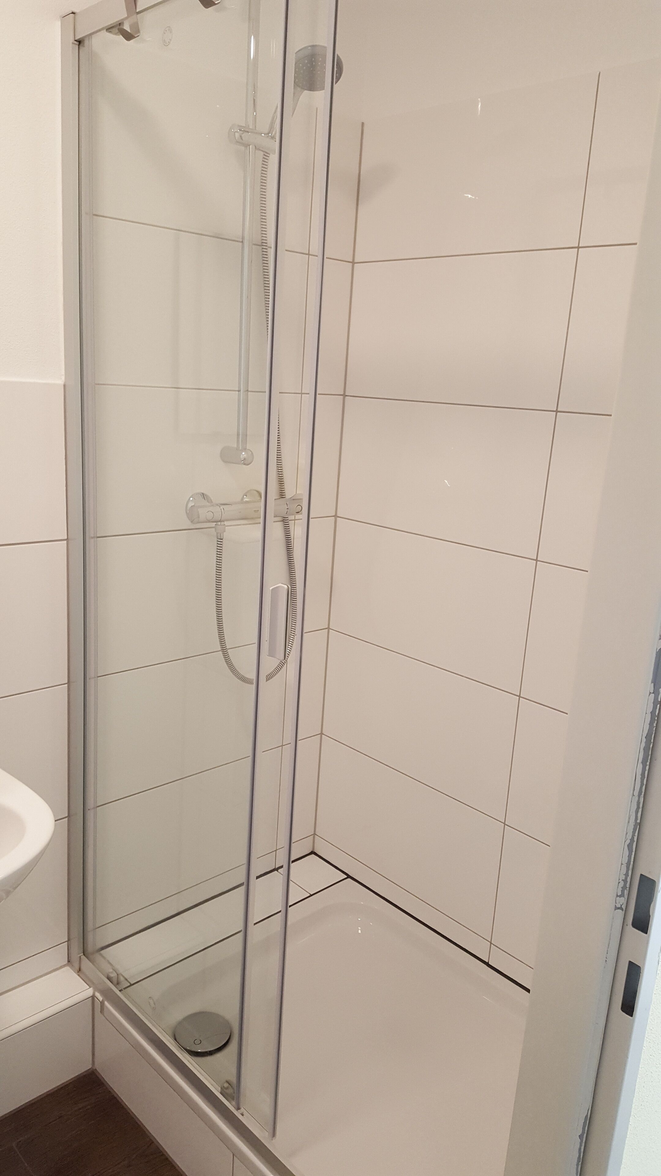 A glass-enclosed shower stall with a handheld showerhead and a control panel.