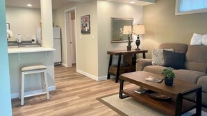 A modern living room with a sofa, coffee table, and a dining area with a kitchen in the background.