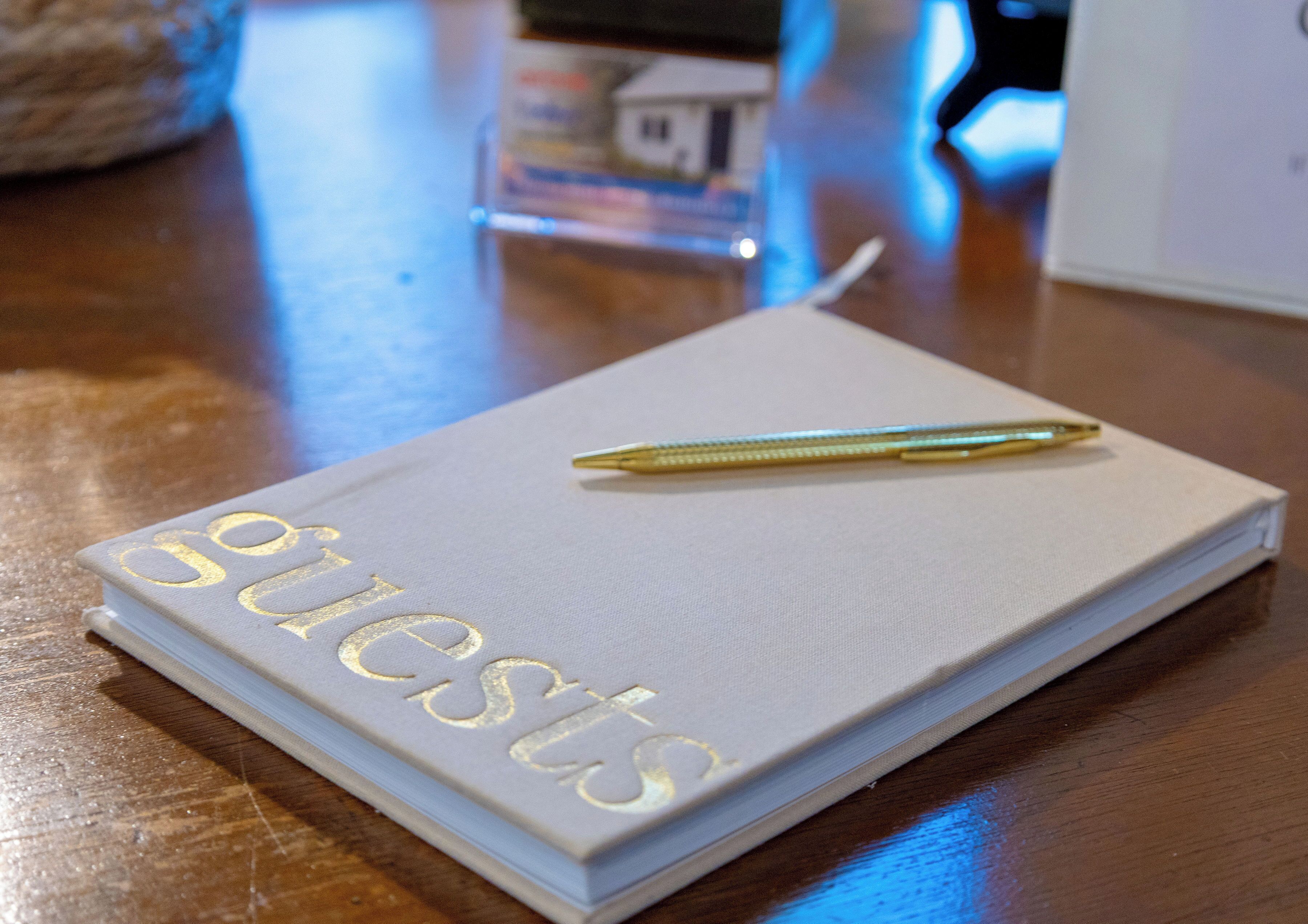 A notebook with the word 'guests' embossed on the cover, placed on a wooden surface.