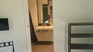A bedroom with a bed, a desk, a chair, and a bathroom visible through an open door. - Villa Petru _T5 Zanzimare Casa (Porticcio)