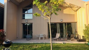 A modern two-story house with a flat roof, large sliding glass doors, and a small tree in the front yard. - Villa Petru _T5 Zanzimare Casa (Porticcio)