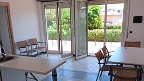 A modern kitchen with a large island, sliding glass doors to a balcony, and a tiled floor.