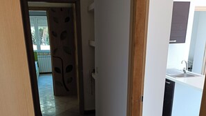 A hallway leading to a kitchen with a sink and a view of a balcony.