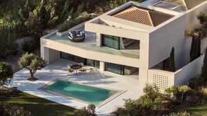 Una casa moderna de dos pisos amb piscina, zona d'estar a l'exterior i jardí ben cuidat.