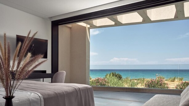 Un dormitori modern amb una finestra gran amb vista a una platja.