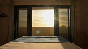 Une chambre avec un lit, une vue sur l’extérieur par une porte coulissante et un panier posé sur le sol.