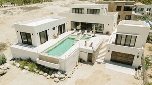 Une maison moderne dotée d’une piscine, de plusieurs balcons et surplombant un paysage désertique.