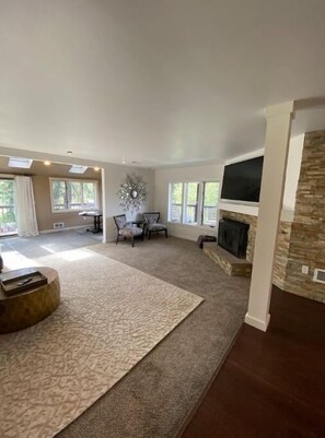 Cozy living room with a fireplace, flat-screen TV, and dining area.