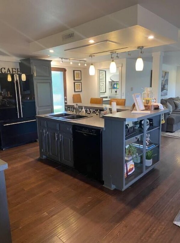 Kitchen features a central island with sink and dishwasher, oven, and glass-fronted cabinet.