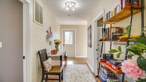 A hallway with a wooden bench, a white rug, and a bookshelf filled with books and board games. - Walk to Shenandoah River: Homey Luray Cabin (Luray)
