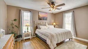 A bedroom with a bed, bedside tables, a ceiling fan, and a window with curtains. - Walk to Shenandoah River: Homey Luray Cabin (Luray)