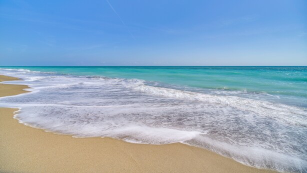 Een strand met helder turquoise water en een zandstrand.