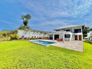 Une maison moderne dotée d’une piscine, d’un patio couvert et d’une pelouse bien entretenue.