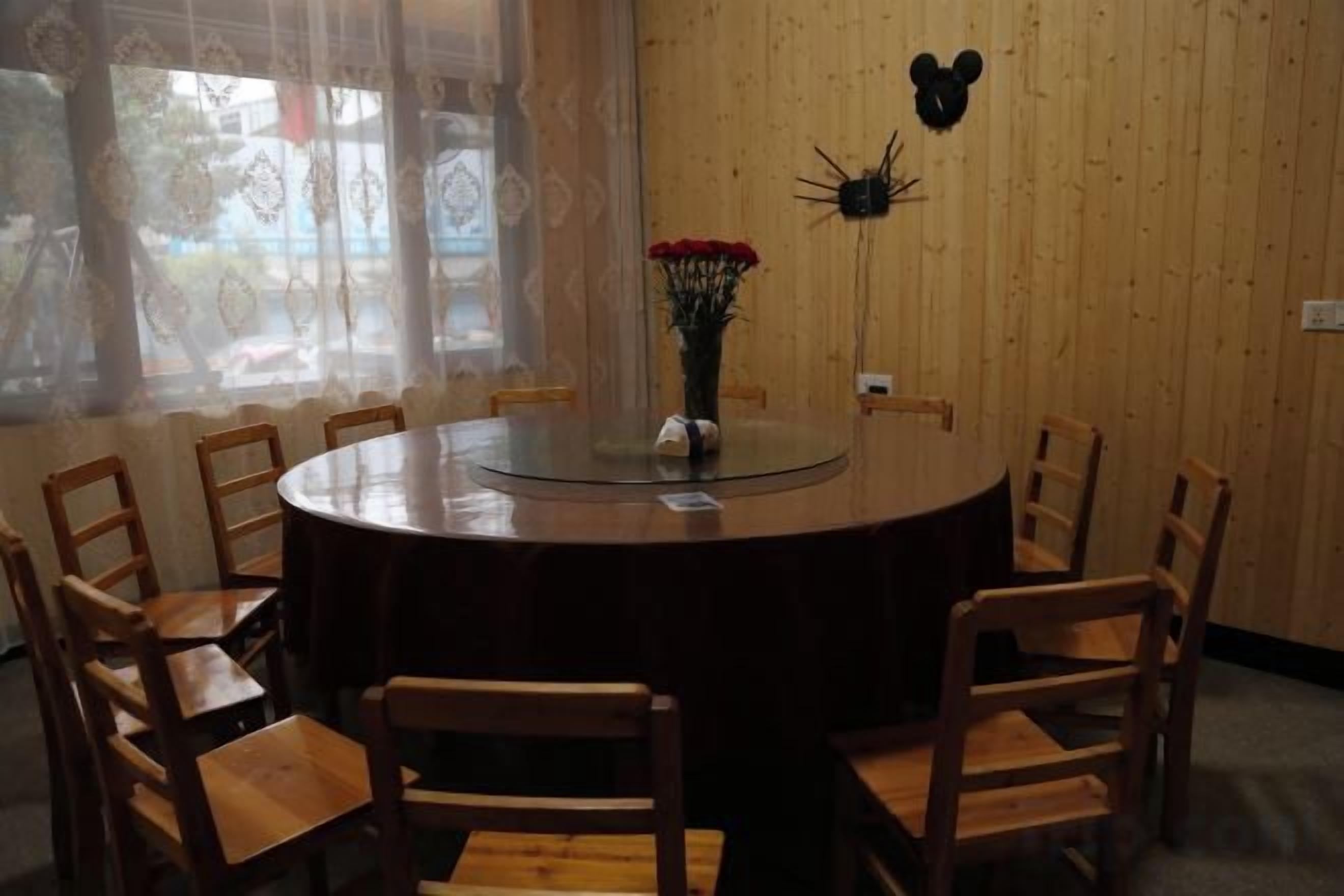 Una mesa redonda para comer con sillas, un florero con flores y un adorno en la pared.