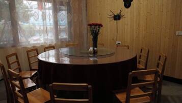 Una mesa redonda para comer con sillas, un florero con flores y un adorno en la pared.