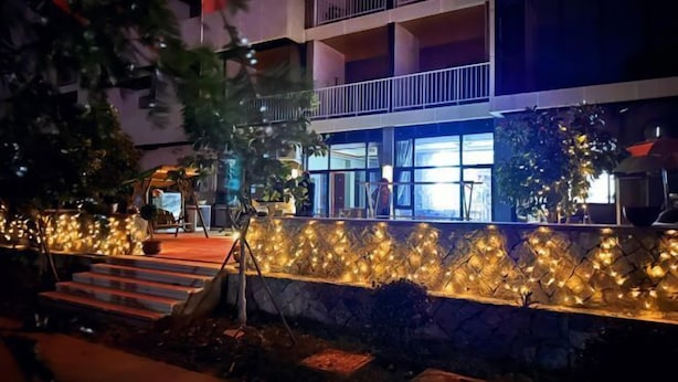 Un immeuble à plusieurs étages doté de balcons, un mur de pierre agrémenté de luminaires et des marches menant à l’entrée.
