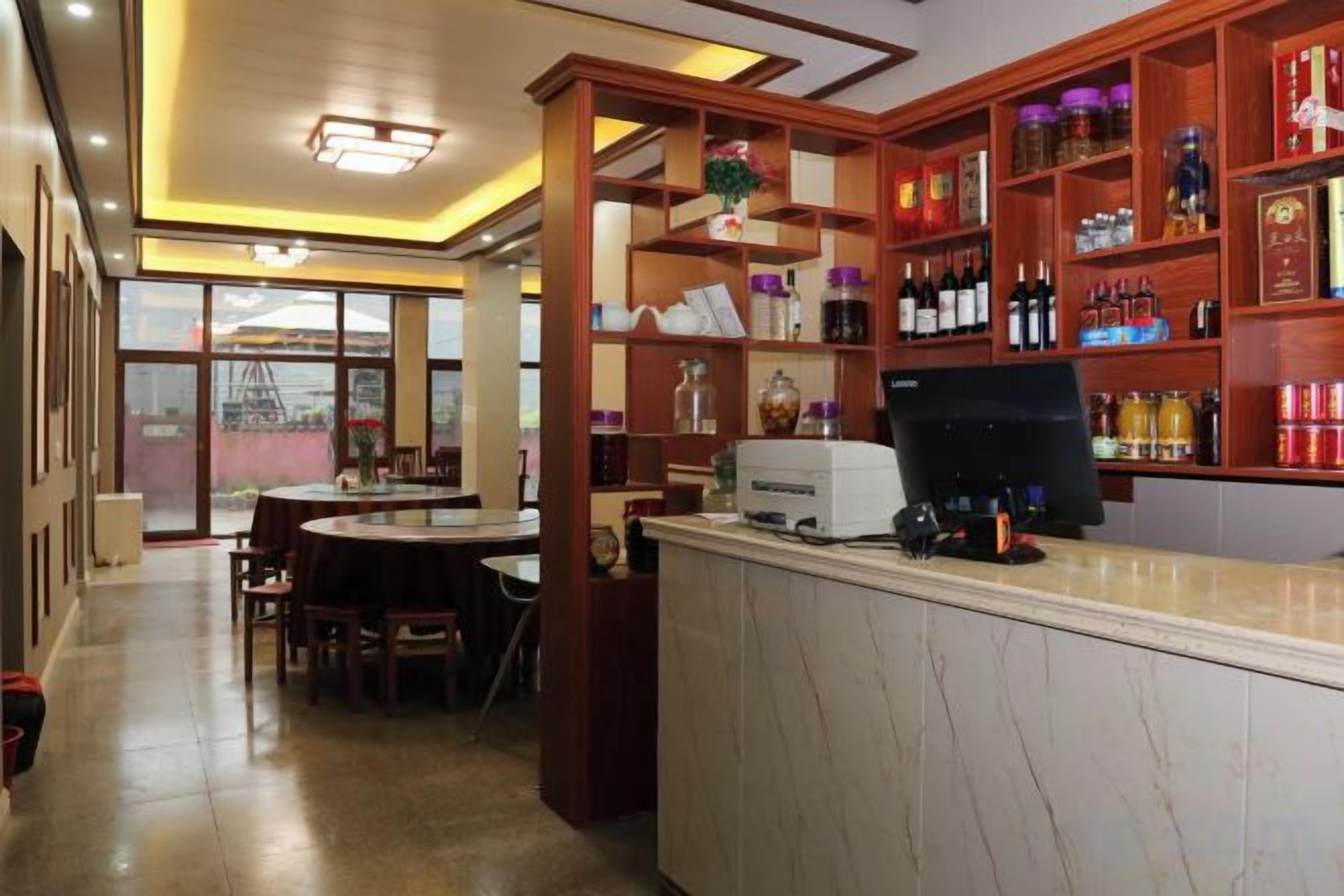 Un restaurante con zona de bar, una mesa de comedor y una barra con ordenador.