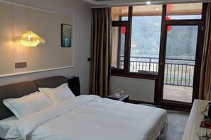 Una habitación de hotel con cama, mesita de noche, lámpara, ventana con cortinas y vista a un balcón.