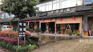 A traditional building with a signboard, outdoor seating, and a wet ground, suggesting recent rain.