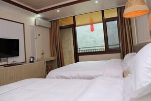 Una habitación de hotel con una cama, televisión y ventana con cortinas.