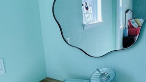Une salle de bain avec un meuble-lavabo en bois, un vasque en verre et un miroir avec un cadre noir.