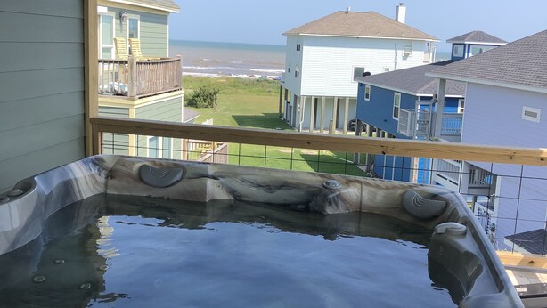 Un bain à remous avec vue sur l’océan et les maisons voisines.