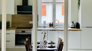 Une cuisine moderne avec un coin repas, des meubles en bois, un four encastré et une vue sur l’extérieur.