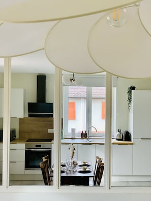 A modern kitchen with a dining area, wooden cabinets, a built-in oven, and a view of the outside.