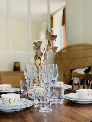 A dining table set with clear glassware and floral-patterned tableware.