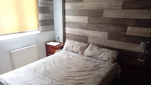 Une chambre à coucher avec un lit, une table de chevet, une lampe et une fenêtre avec des stores.