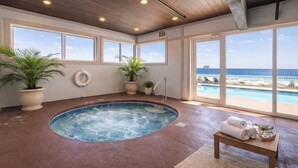 Un espace détente avec un jacuzzi, des plantes en pot, une bouée de sauvetage et une vue sur la plage.