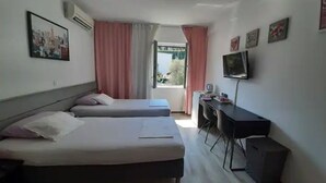 Habitación de hotel con dos camas, un escritorio, un televisor y una ventana con cortinas.