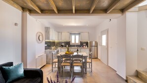 Een compacte keuken met moderne apparatuur, een eethoek met een tafel en stoelen, en een trap naar een ander niveau.