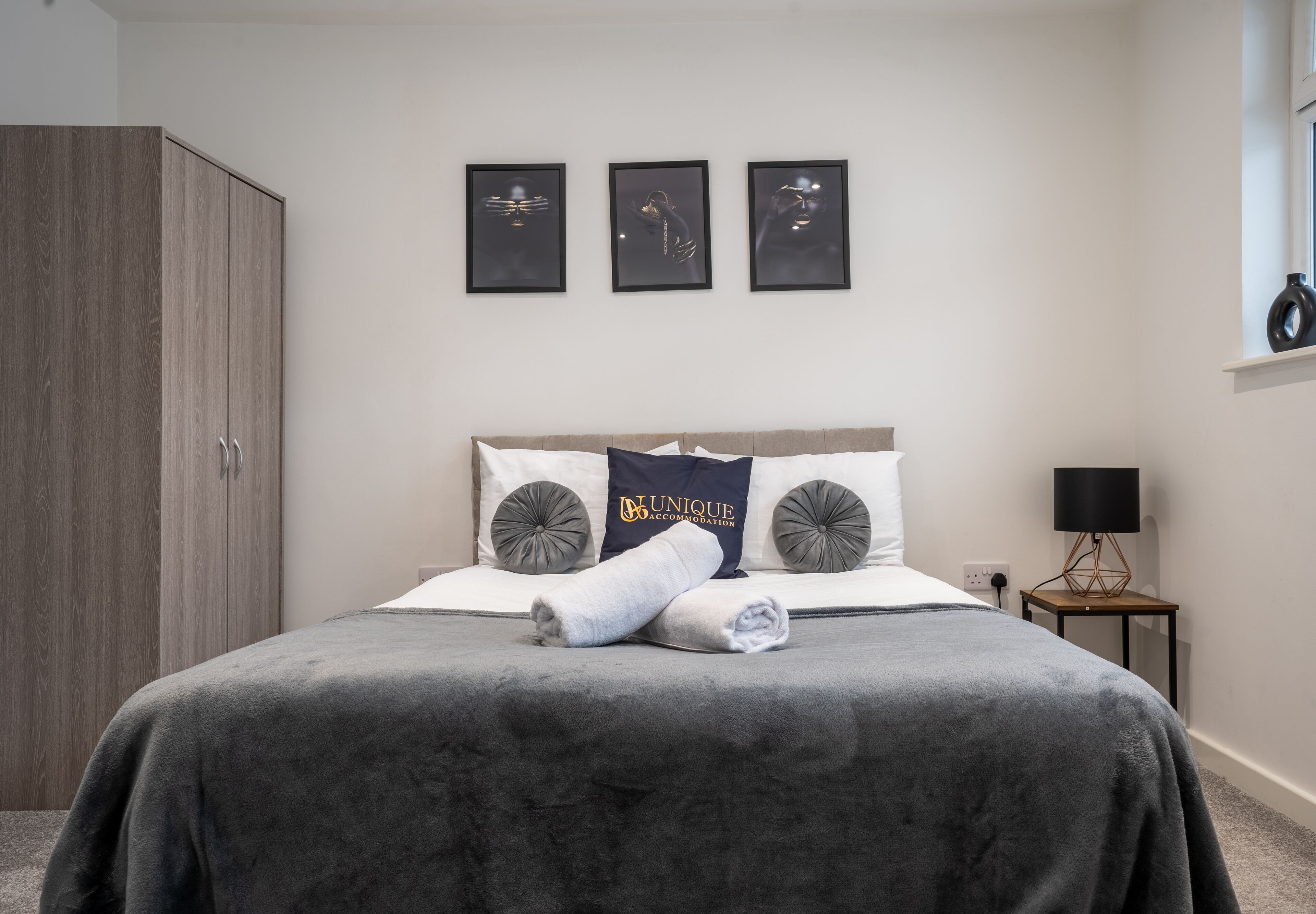 Une chambre à coucher avec un lit, une armoire et trois tableaux encadrés accrochés au mur.