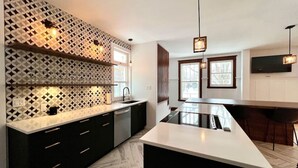 Een moderne keuken met een groot eiland, donkere kastjes en een decoratieve spatwand.