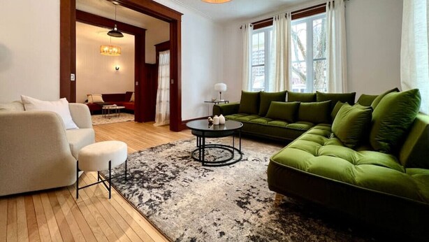 Een moderne woonkamer met een groene bank, een witte fauteuil en een salontafel.