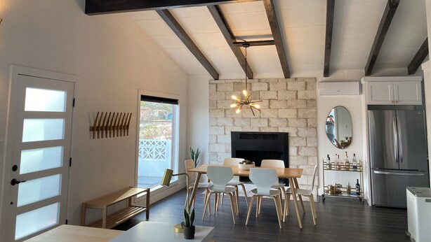 A modern living room with exposed beams, a fireplace, a dining area, and a kitchen with a refrigerator. - Desert Oasis near Downtown Las Vegas (Las Vegas)
