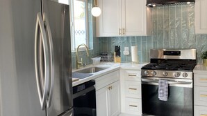 A modern kitchen with stainless steel appliances, white cabinetry, and a dark wooden floor. - Desert Oasis near Downtown Las Vegas (Las Vegas)