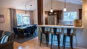 Una cocina moderna con una isla central, taburetes de bar y un comedor con mesa y sillas.
