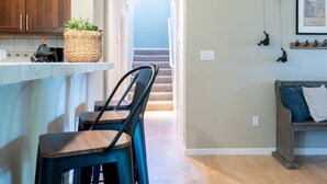 Una cocina con armarios de madera, una barra y una zona de estar con banco y sillas.