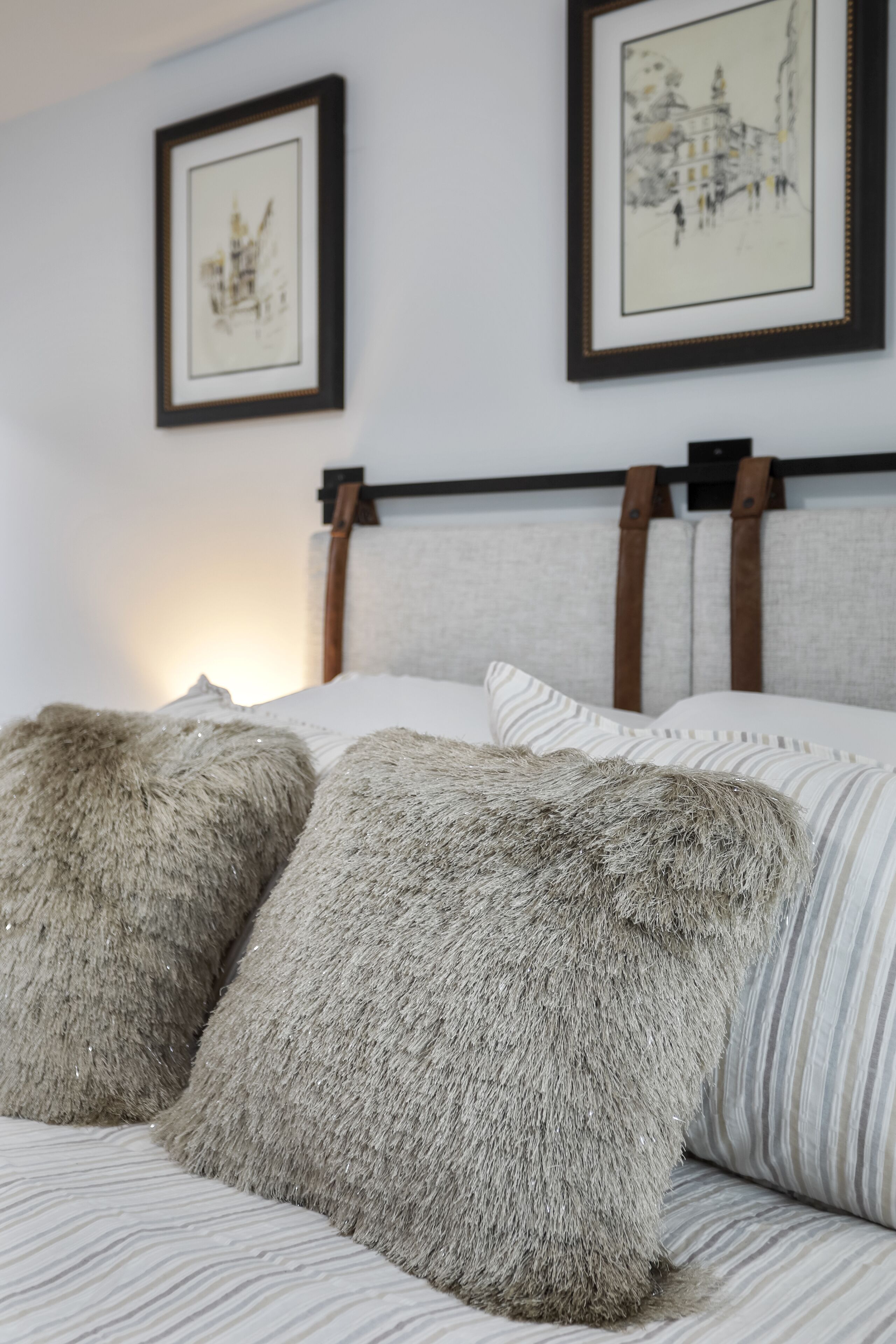 A bed with fluffy pillows and a headboard with leather straps.