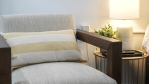 A modern armchair with a striped pillow, a side table with a lamp, and a small plant. - The Knolls (Martinsburg)