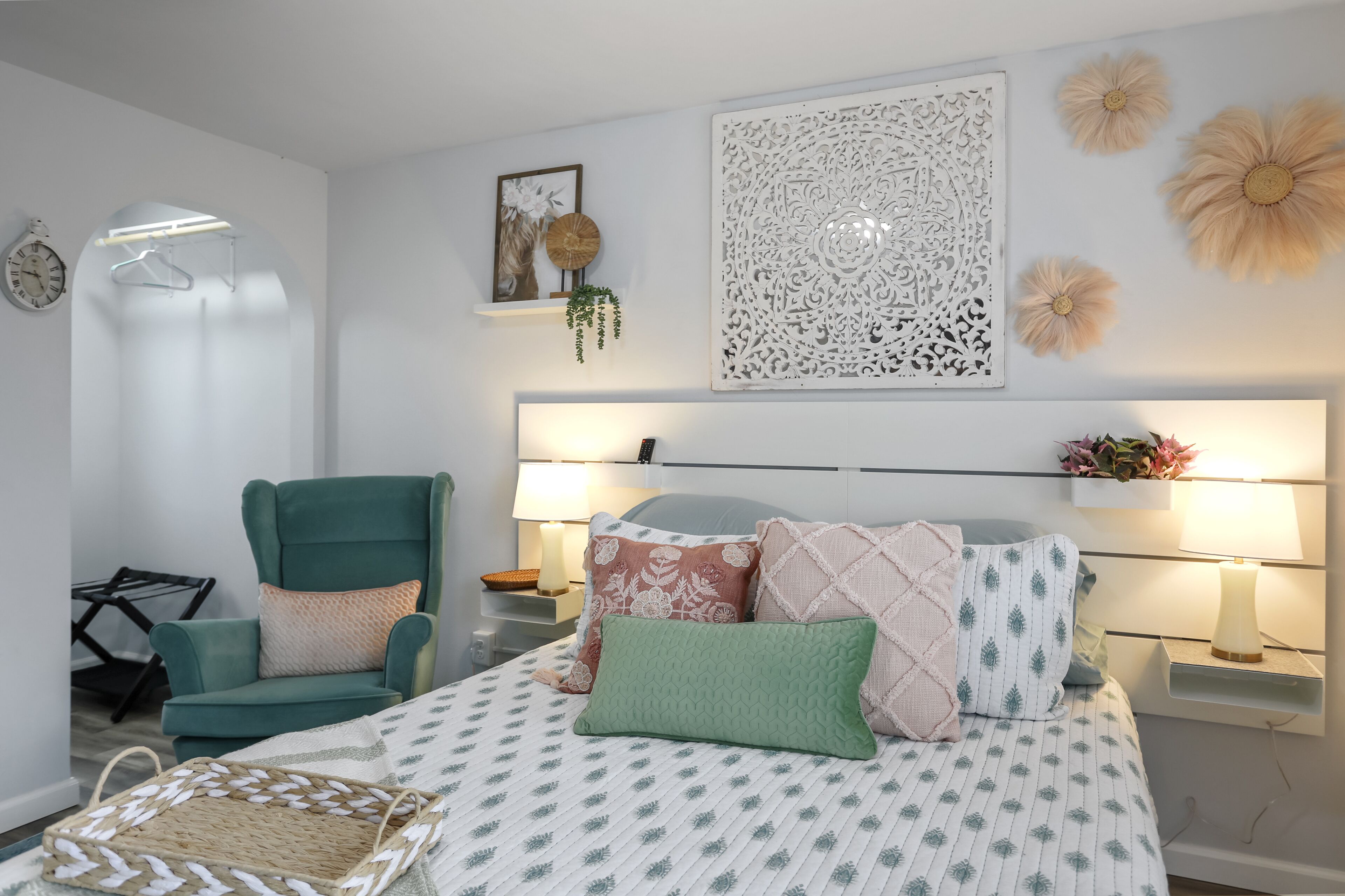 A neatly arranged bedroom with a bed, a chair, a bedside table, and wall decorations.