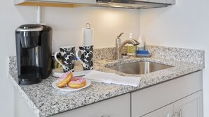 A kitchen with a stainless steel sink, a coffee maker, and a microwave. - The Knolls (Martinsburg)